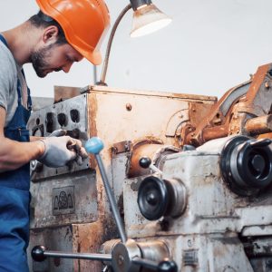 portrait of a young worker in a hard hat at a large metalworking plant. the engineer serves the machines and manufactures parts for gas equipment